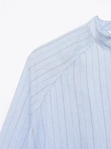 Detailed view of striped shirt collar and raglan sleeve stitching on light blue cotton fabric