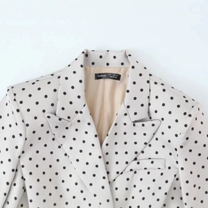 Dettaglio del blazer bianco a pois con revers a lancia e fodera interna color champagne