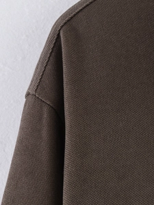 Close-up of high-quality dark brown fabric showing precise stitching and dropped shoulder seam