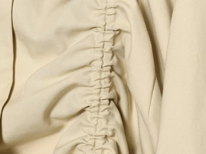 Macro shot of khaki twill fabric detailing central pleated texture and fine stitching
