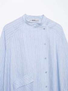 Close-up of light blue striped shirt featuring a mandarin collar and brand label