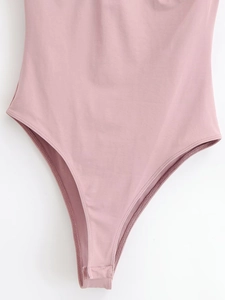 Détail d'un body en maille rose avec fermeture à boutons-pression et coupe échancrée
