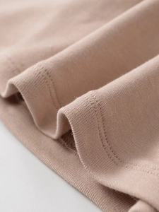 Detailed close-up of double-stitched hem on soft nude knit two-piece set fabric