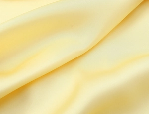 Dettaglio del tessuto di raso giallo liscio con texture setosa ed eleganti pieghe