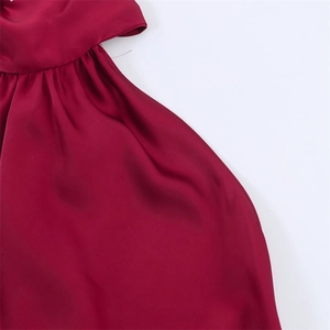 Dettaglio ravvicinato dell'abito in raso rosso scuro con texture di lusso e pieghe eleganti