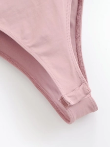 Détail de la fermeture à boutons-pression à l'entrejambe d'un body rose ajusté pour femme