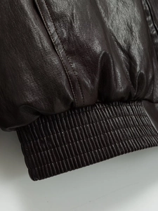 Dettaglio giacca in pelle marrone scuro con bordo elastico a coste e doppie cuciture fini