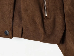 Detail of brown faux suede jacket hem featuring silver snap button and metal zipper