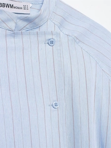 Detail of light blue striped shirt featuring a mandarin collar and decorative buttons