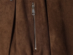 Close-up of a silver zipper detail on a dark brown faux suede biker jacket pocket
