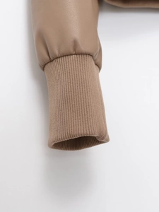 Detailed macro view of brown faux leather jacket cuff with elastic ribbed knit trim finish