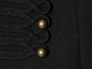 Detailed view of military-style black jacket with braided frogging and gold buttons