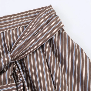 Detail of striped shorts featuring a brown and blue vertical pattern with a waist tie bow