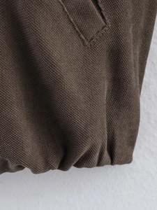 Macro detail of brown jacket hem featuring elastic ribbing and neat stitching texture