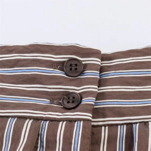 Detail of waist design with stripes, resin buttons and elegant pleats on shorts