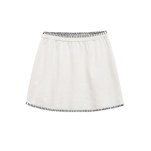 Close-up of white knitted skirt featuring bold black contrast stitching on hem and waist