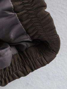 Close-up of brown herringbone jacket with gray lining and elastic ribbed cuff detail