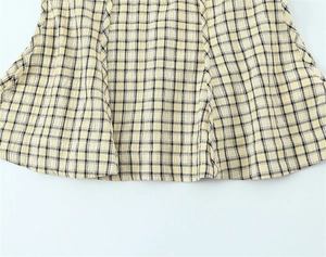 Detail of yellow plaid seersucker fabric showing textured weave and stitched hem finish