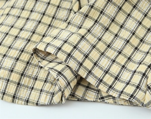 Macro view of light yellow and black plaid seersucker fabric with neat hem stitching
