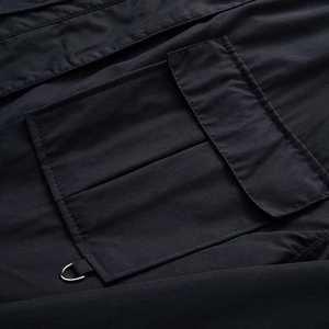 Detail of black utility jacket featuring a flap pocket and metallic D-ring hardware