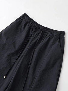 Detail of elastic waist joggers with adjustable black drawstring and gold metal tips