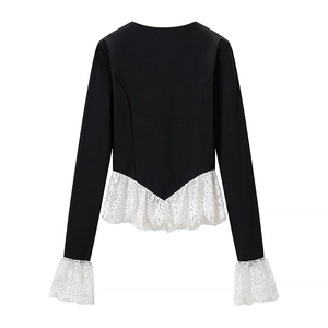 Detailed view of women's black long sleeve top with white lace hem and cuff contrast