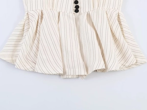 Close-up of pinstripe blazer waist with black buttons and pleated ruffle hem detail
