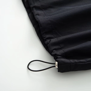 Close-up of black jacket hem with elastic drawstring and silver metal cord lock detail