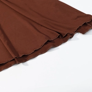 Detail shot of the caramel brown knit dress showing the delicate lettuce edge hemline