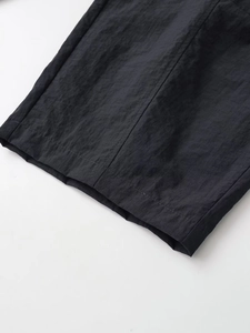 Detailed close-up of the black nylon bucket pants showing stitching and quick-dry fabric