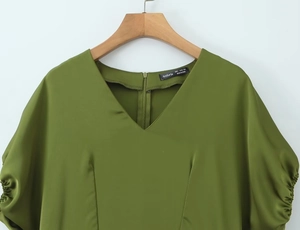 Detail view of olive green V-neck dress with gathered sleeves and concealed back zipper