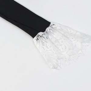 Detailed view of black sleeve cuffs featuring delicate white floral lace with eyelash trim