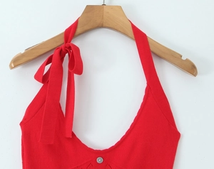 Detail of red knit halter dress featuring tie-up bow shoulder and U-neck with silver button