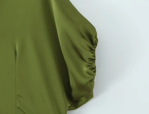 Macro view of olive green dress featuring ruching details and satin sheen texture
