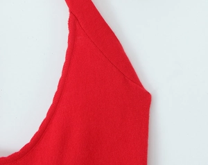 Close-up of bright red knit dress showing fine texture and ribbed neckline detail