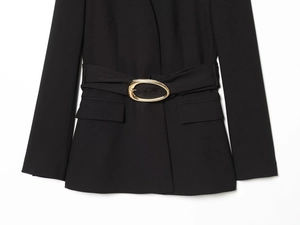 Détail d'un blazer noir avec boucle de ceinture dorée ovale et poches à rabat élégantes