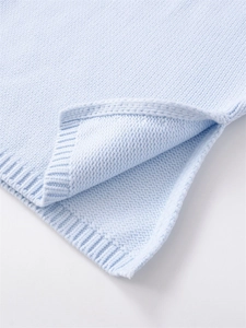 Detail of light blue knit sweater featuring ribbed hem texture and stylish side slit