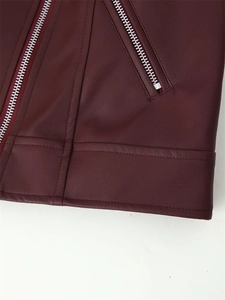 Détail de la veste en cuir bordeaux montrant la texture et les fermetures éclair argentées