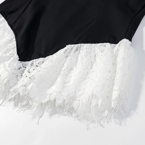 Close-up of black fabric with intricate white eyelash lace trim on the garment edge