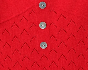 Detailed macro shot of red knit fabric with pearl buttons and hollow out patterns