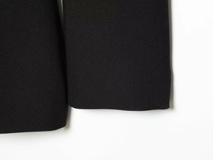 Gros plan sur la texture du tissu noir et les coutures de l'ourlet de la veste