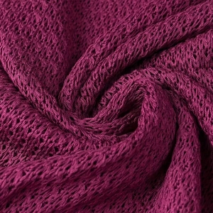 Macro shot of burgundy knitted fabric showing detailed hollow mesh texture and pattern