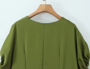 Detail of green dress featuring round neck, back zipper and pleated sleeve texture