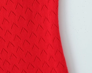 Detail view of red slim knit dress featuring intricate V-shaped pointelle stitching texture