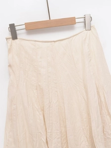 Detail of light beige midi skirt showing natural wrinkled cotton linen fabric texture