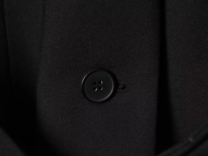 Vue macro du bouton noir mat à quatre trous et de la texture sergée du blazer