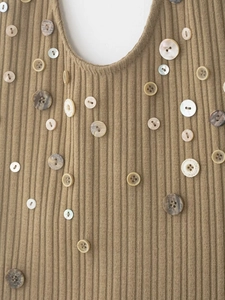 Detail of khaki ribbed knit top featuring various decorative buttons and textures