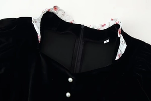 Detail of velvet dress collar with floral ruffle trim and decorative pearl buttons