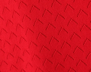 Detail of red knit fabric featuring breathable V-shaped hollow-out textured patterns