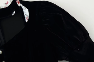 Detail of velvet dress collar with floral ruffle trim and pearl button embellishment
